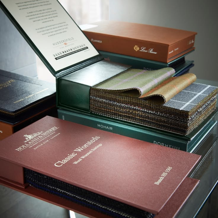 Suits on the rack and fabric books in the Atelier Sareno showroom
